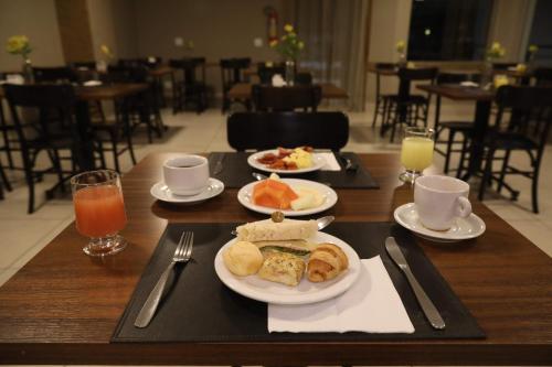 a table topped with plates of food and drinks at Golden Tulip Goiania Address in Goiânia