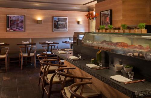 a restaurant with a bar with stools and a counter with food at The Eliot Hotel in Boston