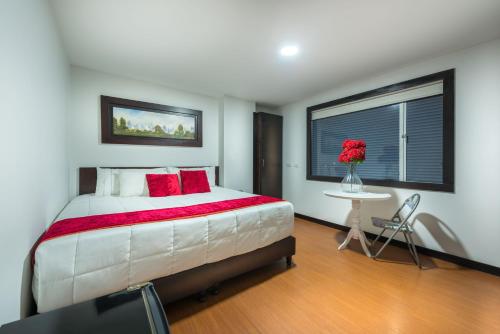 Un dormitorio con una cama grande con almohadas rojas y una ventana en Hotel Bogota Resort, en Bogotá