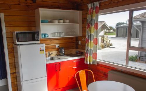 cocina con nevera, fregadero y ventana en Little Wanganui Hotel, en Little Wanganui