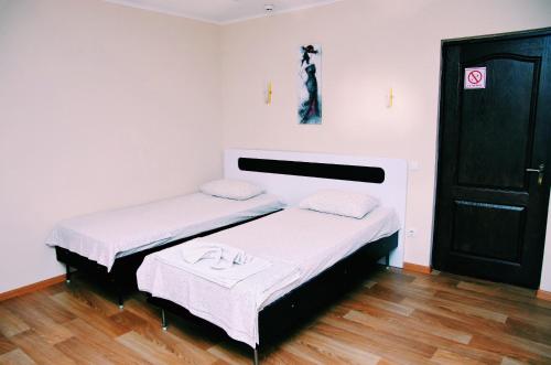 two beds in a room with white walls and wooden floors at Hotel and Entertaiment Complex Vlada in Cherkasy
