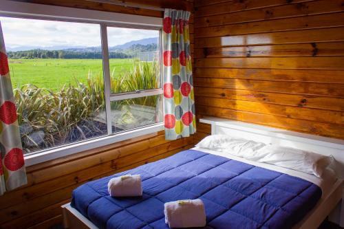 Little Wanganui Hotel في Little Wanganui: غرفة نوم بسرير ازرق ونافذة كبيرة