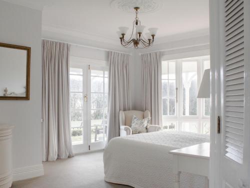 a white bedroom with a bed and a chandelier at Goodin Country Garden in Okato