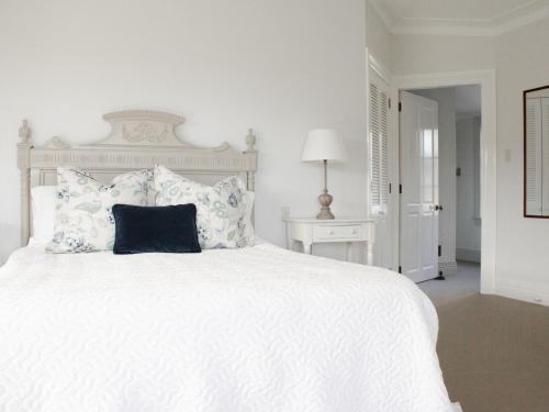 a white bedroom with a large white bed with a black pillow at Goodin Country Garden in Okato