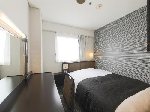 um quarto com uma cama, uma secretária e uma janela em APA Hotel Yamagata Tsuruoka Ekimae em Tsuruoka