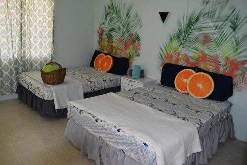 2 Betten in einem Zimmer mit orangefarbenen Kissen in der Unterkunft Posada del Mar in La Parguera
