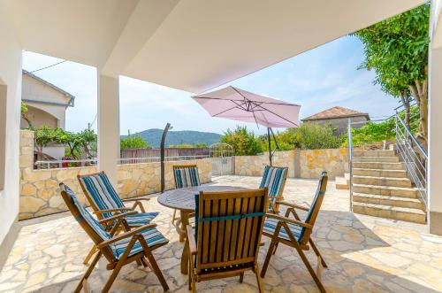 a patio with a table and chairs and an umbrella at House Ivana in Vinišće