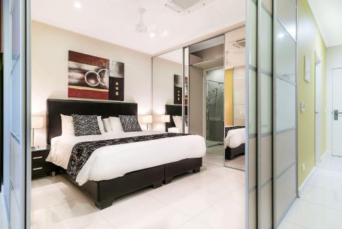 a bedroom with a large bed and a glass wall at Elsey on Parap in Darwin