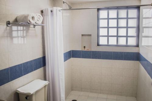 a bathroom with a shower and a toilet and a window at Múcara hotel in Veracruz