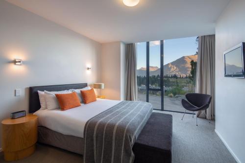 a hotel room with a bed and a large window at Panorama Terrace Apartments - Element Escapes in Queenstown