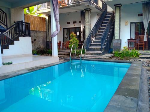 una piscina frente a una casa con escaleras en Rumahku Homestay, en Amed