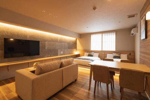 a hotel room with a bed and a couch and a table at GRAND BASE Iolani in Beppu