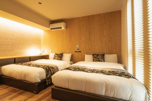 two beds in a hotel room with at GRAND BASE Iolani in Beppu