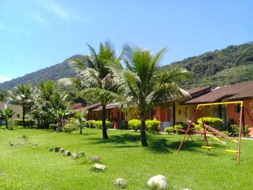 a yard with a playground and palm trees and a house at Pousada Ana e o Mar in Ubatuba
