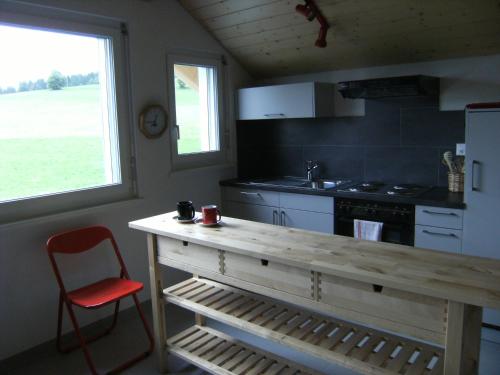 una cucina con bancone in legno e sedia rossa di BnB Niederer a La Côte-aux-Fées