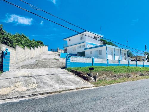 a house with a blue fence on the side of a road at The Hill Inn at Arecibo 681 Ocean Drive in Arecibo