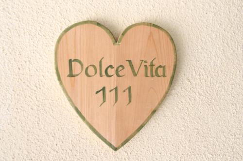 a wooden heart with the words dodice vita on a wall at Klimahaus Dep. La Fradora in San Cassiano