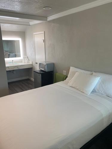 1 dormitorio con 1 cama blanca grande y lavamanos en Elmwood Motel, en Auburn