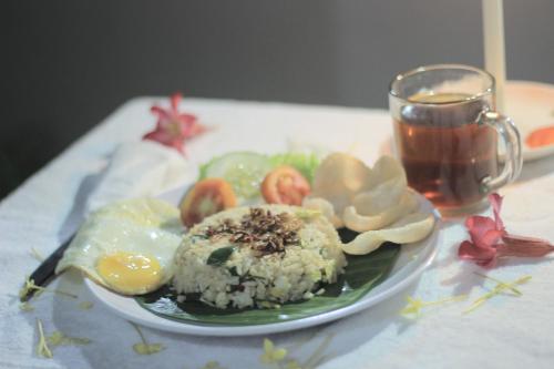 a plate of food on a table with a cup of tea at Wisma Andany in Jepara
