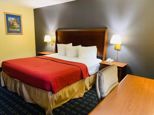 a hotel room with a bed with a red blanket at Value Lodge - Gainesville in Gainesville