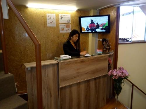 eine Frau, die an einer Theke in einem Zimmer mit einem TV sitzt in der Unterkunft Posada SAQRA Cusco in Cusco