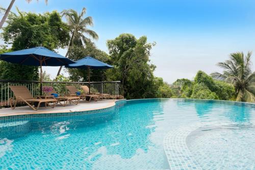 a swimming pool with two chairs and umbrellas at The Park Surin Serviced Apartments by RESAVA in Surin Beach