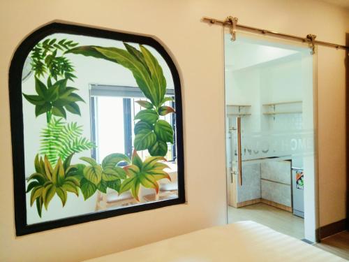 a mirror on a wall with a painting of plants at ENJOY HOME in Da Nang