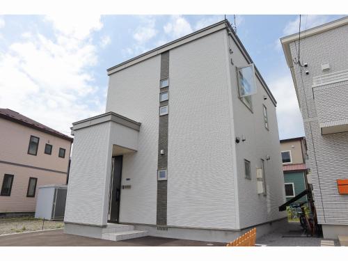 a white building with a door on the side of it at Monochrome Hakodate in Hakodate