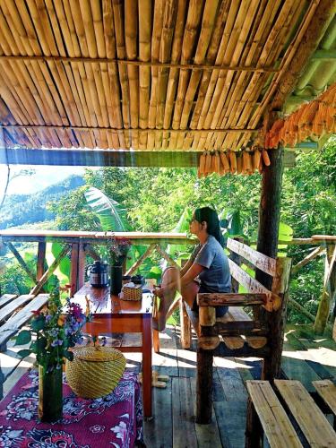 a woman sitting on a bench under a wooden roof at ChienDe Homestay in Sa Pa