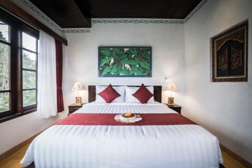 a bedroom with a large white bed with red pillows at Villa Tanah Carik by Mahaputra in Tegalalang