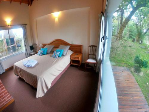 a bedroom with a bed and a large window at Haras del Bosque in Mar de las Pampas