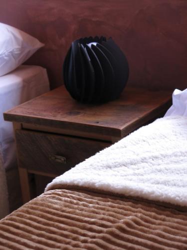 a black vase sitting on a wooden table next to a bed at Casatilcara Cabañas in Tilcara