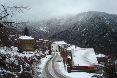 a snow covered village with a road and a mountain at Elatou in Áno Khóra