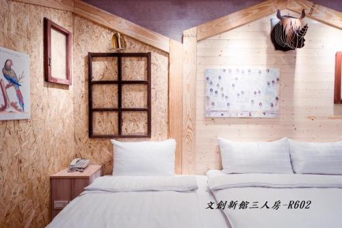 a bedroom with two white beds and a wooden wall at At Tainan Inn in Tainan