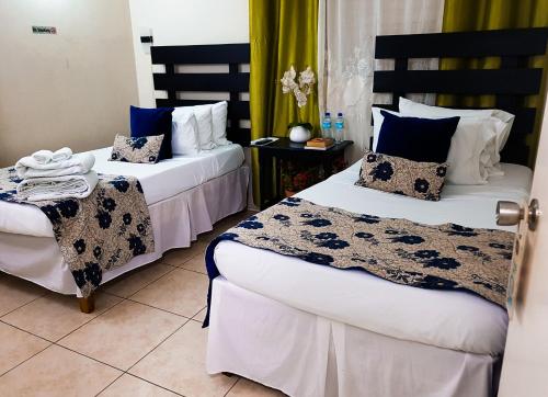 2 letti in una camera d'albergo con blu e bianco di Eventuality B&B New Kingston a Kingston