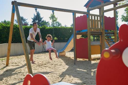 a man and a little girl playing on a swing at Village de Montmarsis in Gourdon-en-quercy