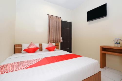 een slaapkamer met een bed met rode kussens en een televisie bij Super OYO 1250 Unta Residence in Semarang