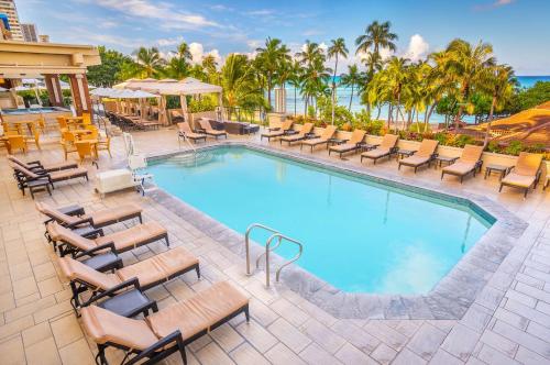 
a pool with chairs and tables in it at Hyatt Regency Waikiki Beach Resort & Spa in Honolulu

