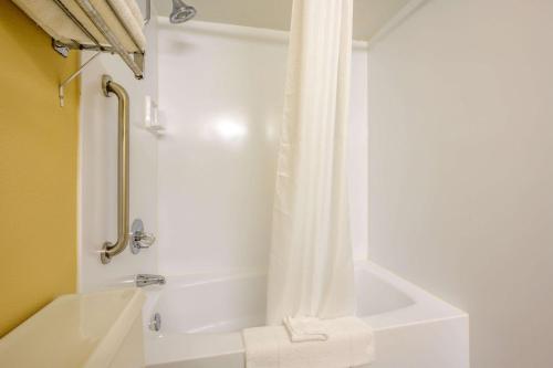 a bathroom with a tub and a shower with a shower curtain at Econo Lodge Inn & Suites Triadelphia - Wheeling in Triadelphia