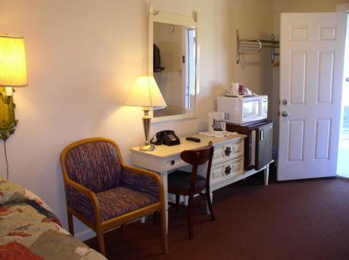 a hotel room with a desk and a bed and a room at Hacienda Motel in Alturas