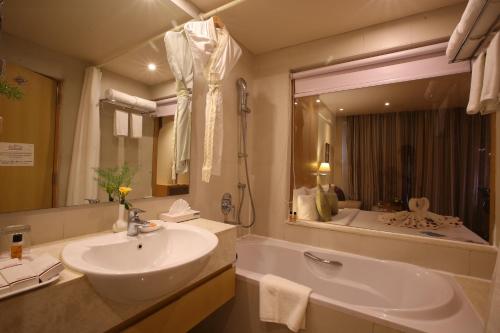 a bathroom with a sink and a tub and a mirror at The Chancery Hotel in Bangalore