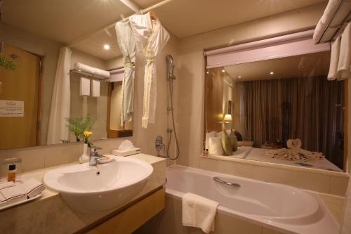a bathroom with a sink and a tub and a mirror at The Chancery Hotel in Bangalore
