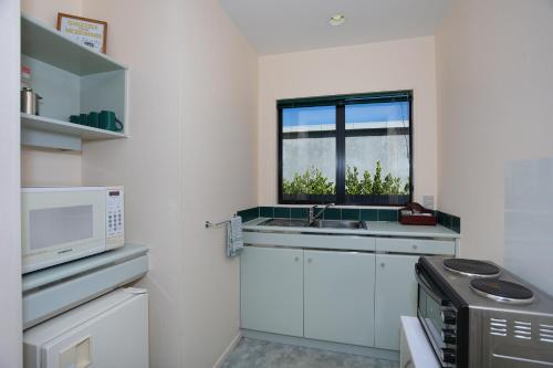 a kitchen with a sink and a microwave at Pavilion Motel & Conference Centre in Palmerston North