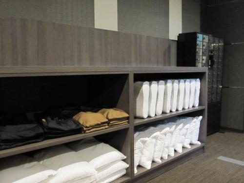 a shelf filled with lots of white towels at BIZCOURT CABIN SUSUKINO (Male Only) in Sapporo