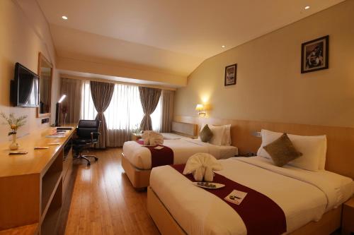a hotel room with two beds and a desk at The Chancery Hotel in Bengaluru
