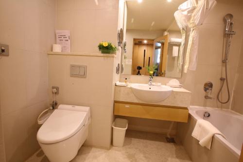 a bathroom with a toilet and a sink and a tub at The Chancery Hotel in Bengaluru
