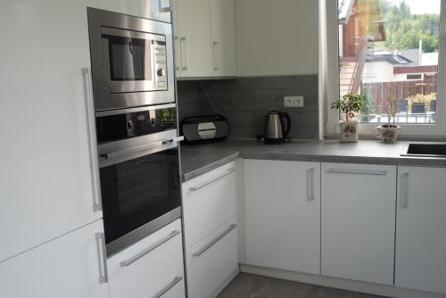 a kitchen with white cabinets and a microwave at Vila pod Černou horou in Rožnov pod Radhoštěm