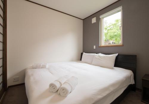 una camera da letto con un grande letto bianco con asciugamani di Ezo Yuki a Niseko
