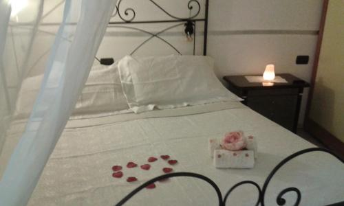 Dormitorio con cama con edredón blanco y caja de rosa en Casa in collina "la farfalla", en Riparbella
