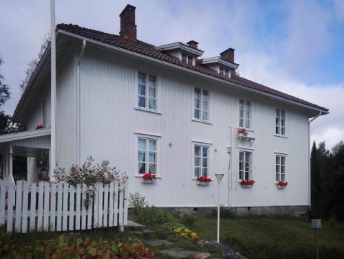 een wit huis met rode bloemen op de ramen bij Kyykerin Kartano in Outokumpu